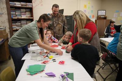 an owl festival volunteer helps a family with crafts.